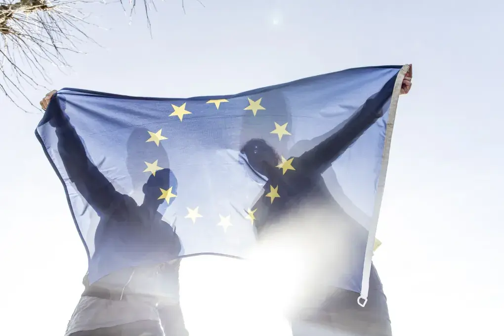 Deux personnes tiennent un drapeau européen.