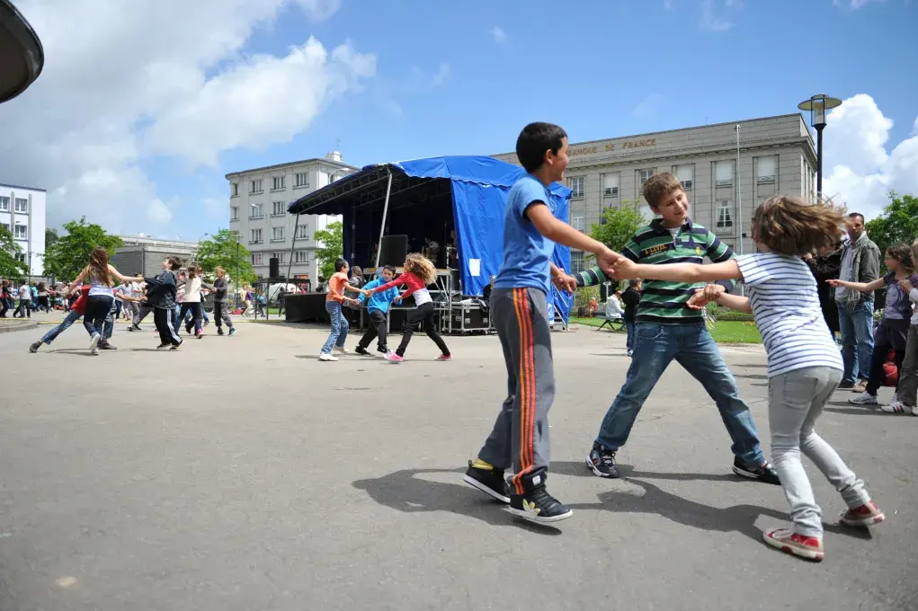 Des enfants en train de danser au milieu d'une place.