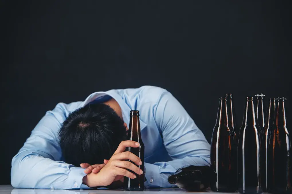 Un homme dort près de bouteilles d'alcool.