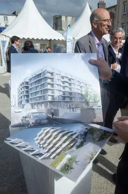 Une personne tient deux affiches de projets immobiliers.