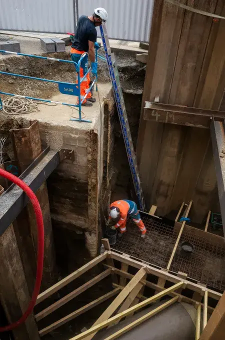 Deux ouvriers en train de travailler dans un trou.