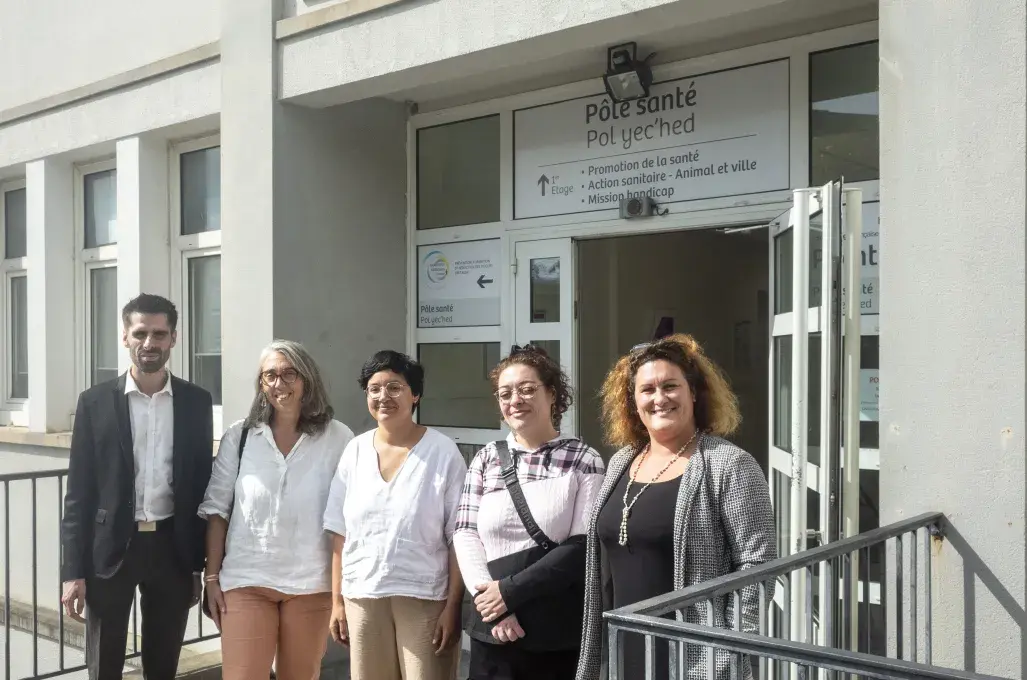 Plusieurs personnes posent devant un bâtiment. 