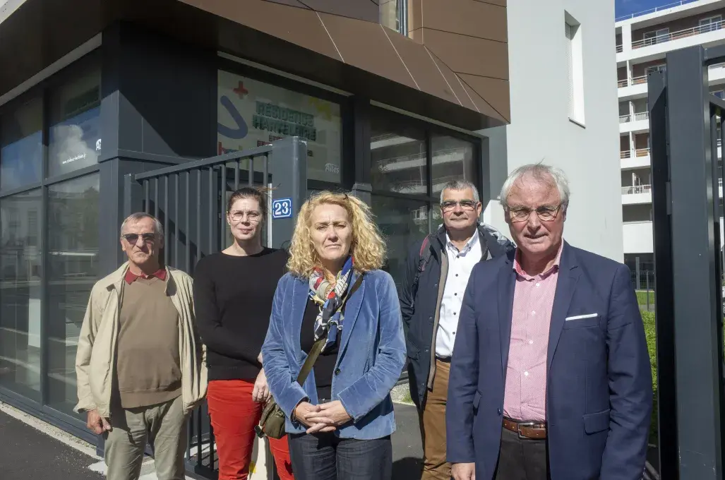 Plusieurs personnes posent devant un bâtiment. 