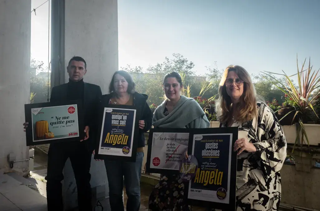 Quatre personnes tiennent des affiches.