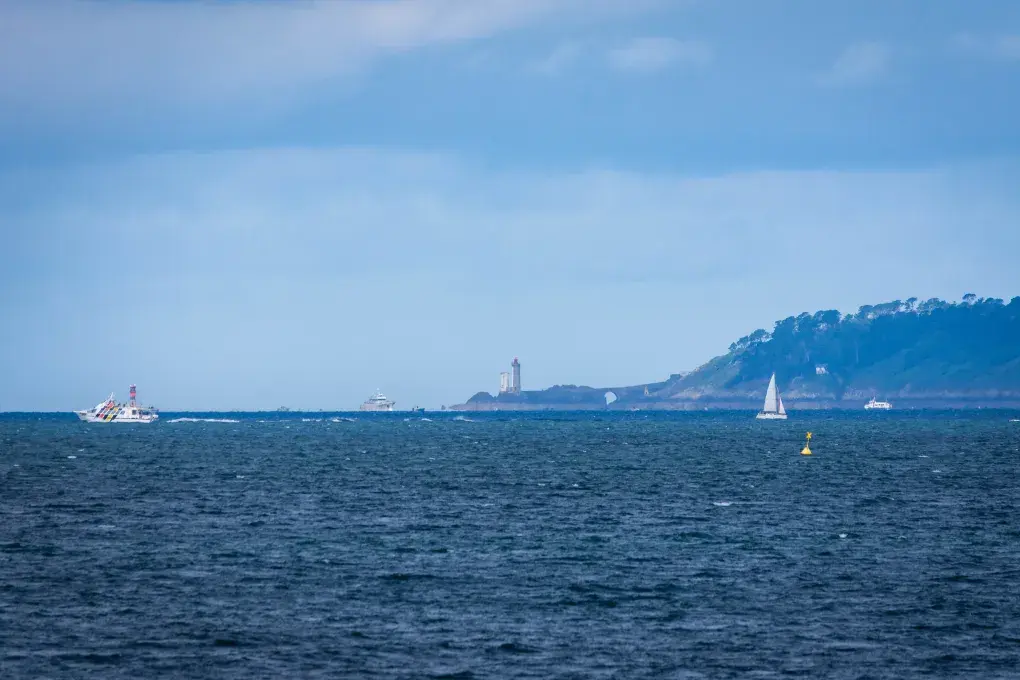 Large vue sur un océan avec un phare au loin.