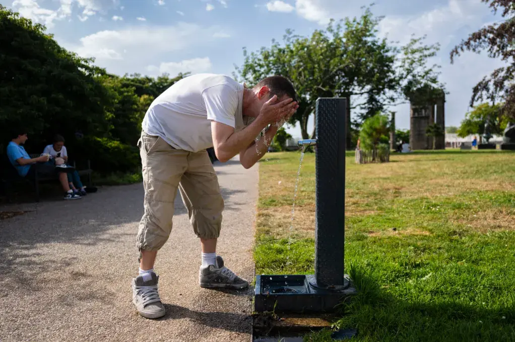 Une personne boit de l'eau à un robinet public