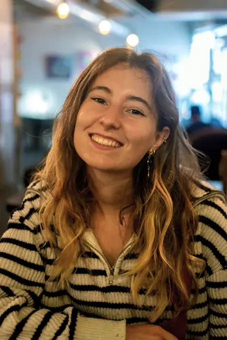 une jeune fille souriante attablée 