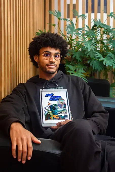 Un jeune homme assis présentant une tablette graphique