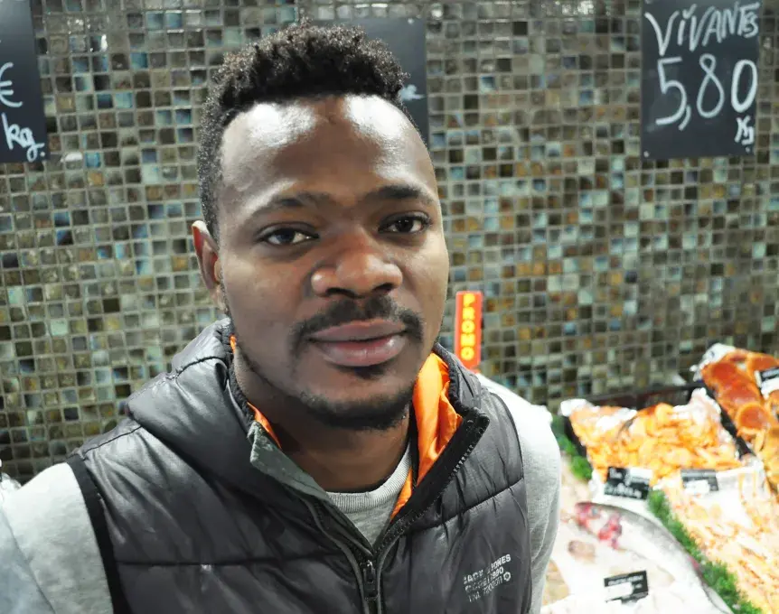 Un jeune homme devant un étal de poissons