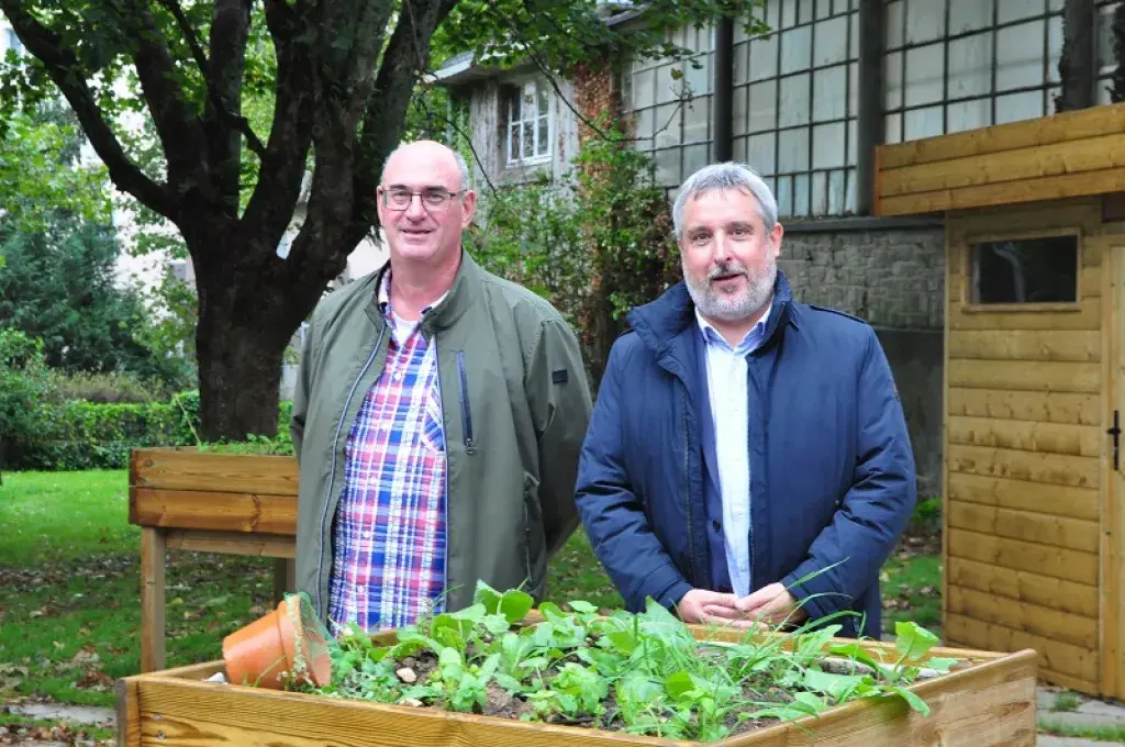 Deux hommes posent devant un bac à fleurs d'un jardin partagé à Brest.