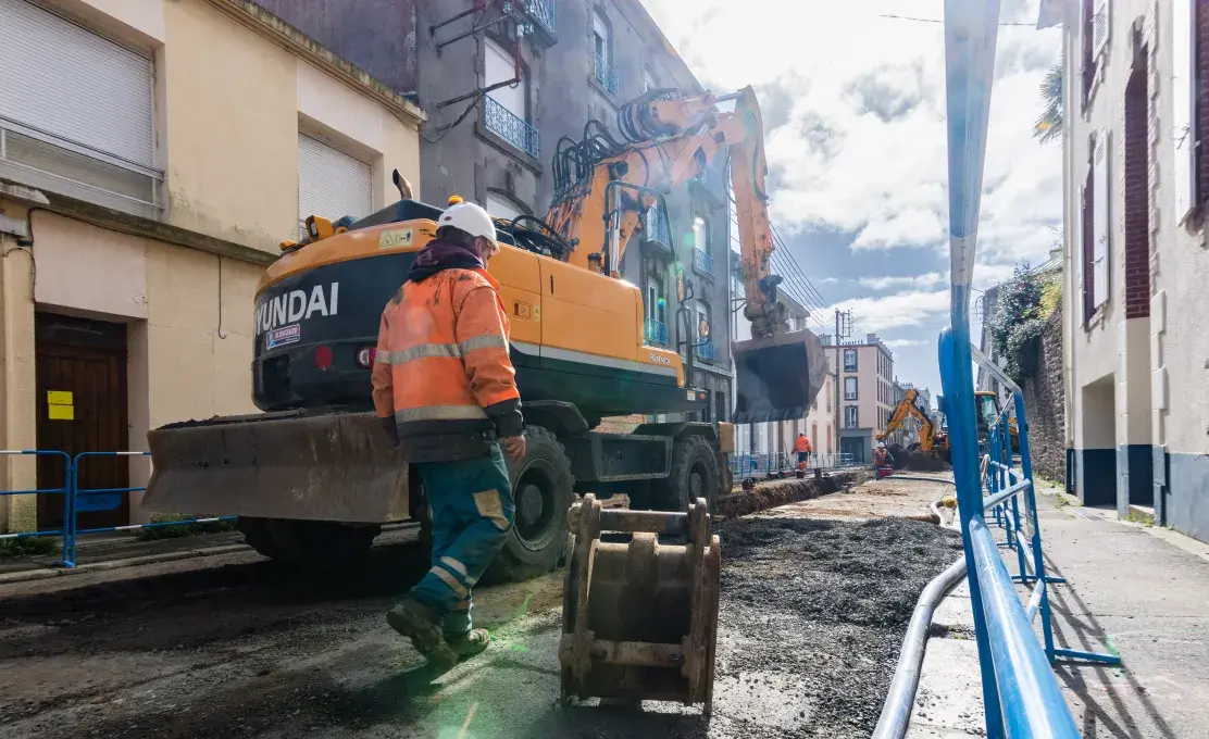 Un homme à côté d'une pelleteuse lors d'un chantier de travaux publics