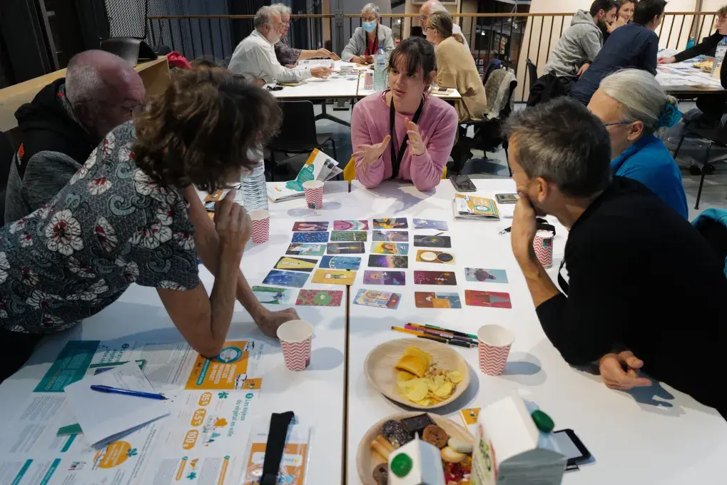 Des personnes réunies autour d'une table parlant autour d'un jeu de cartes