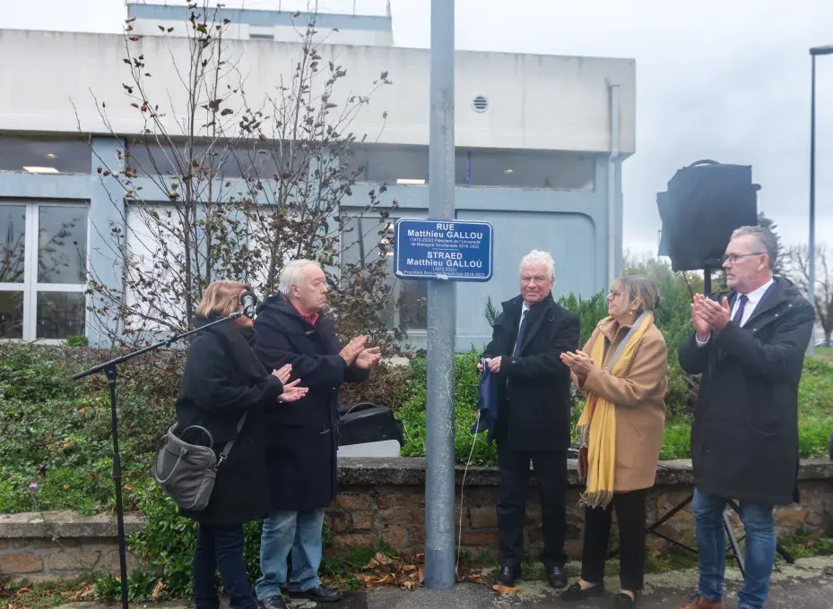 Plusieurs personnes devant une plaque de rue.