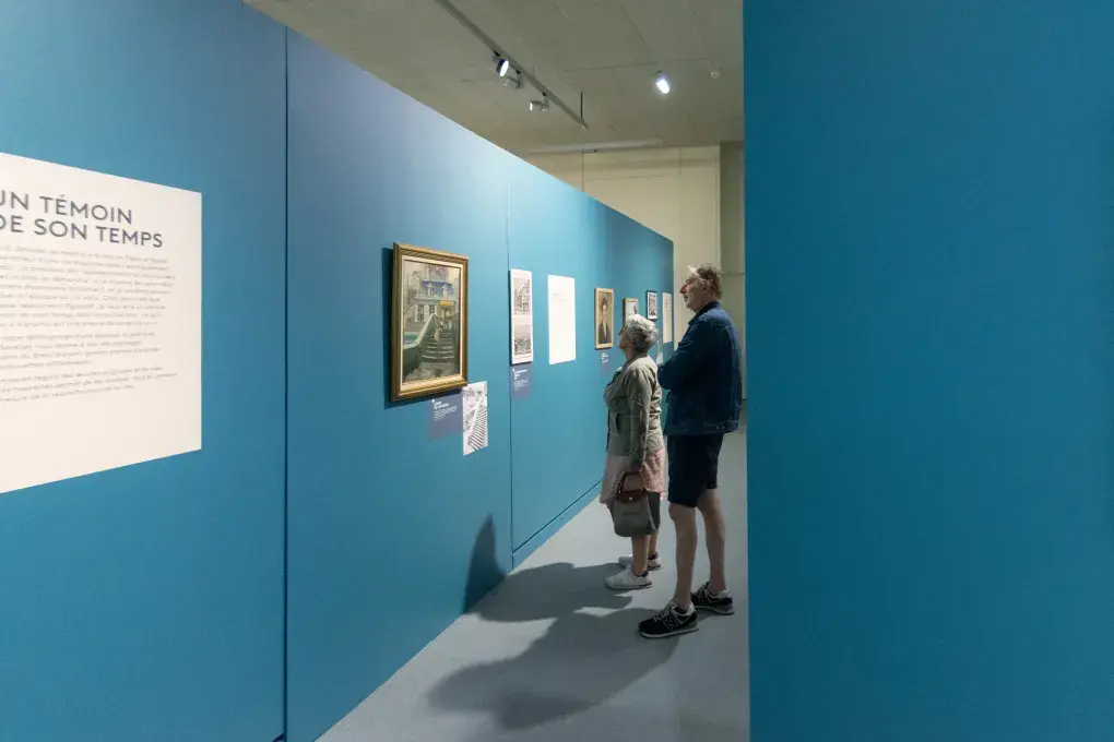 Deux personnes regardent des tableaux.