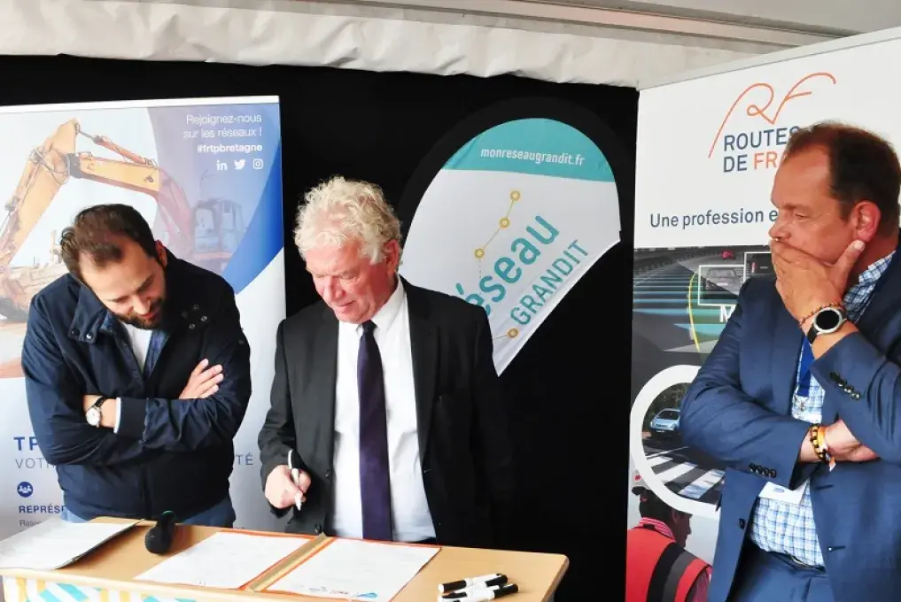 Trois hommes signet une convention à un pupitre