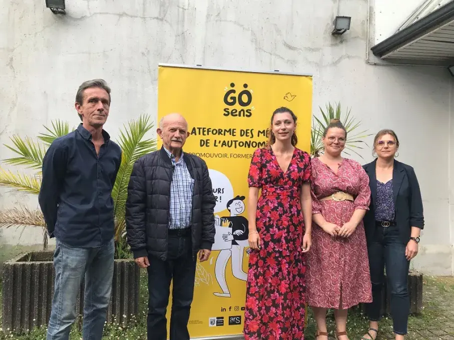 Des hommes et des femmes posent devant l'affiche du Go sens tour.