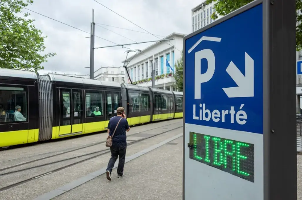 Un homme passe devant le tram, à proximité du panneau d'accès au parking couvert de la place de la Liberté