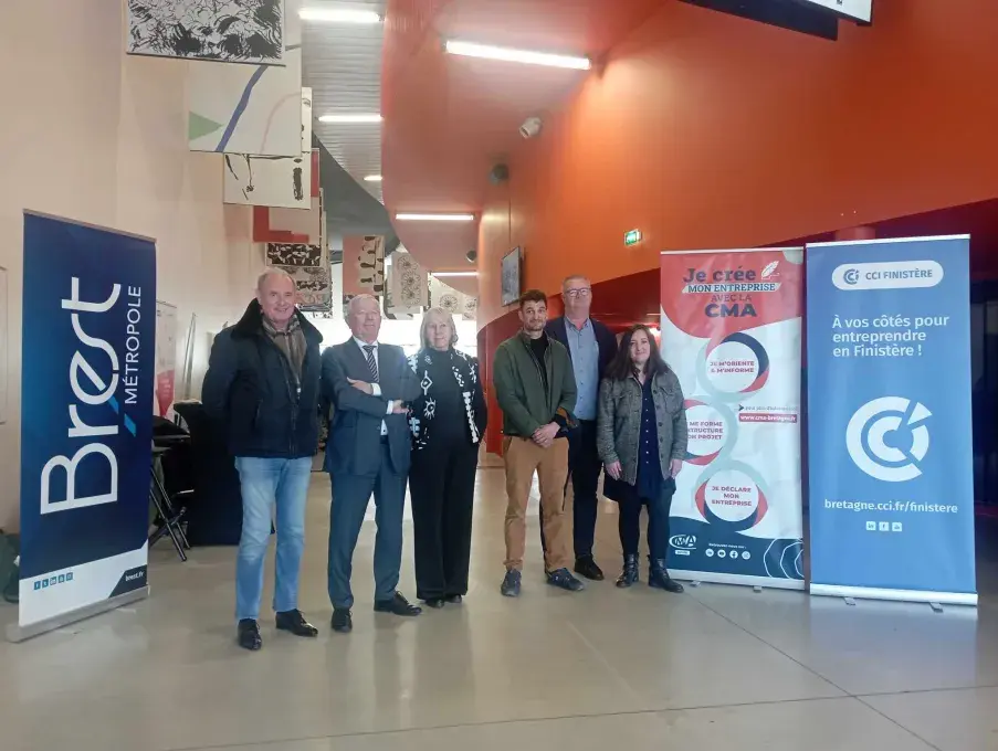 Plusieurs personnes posent devant des affiches.