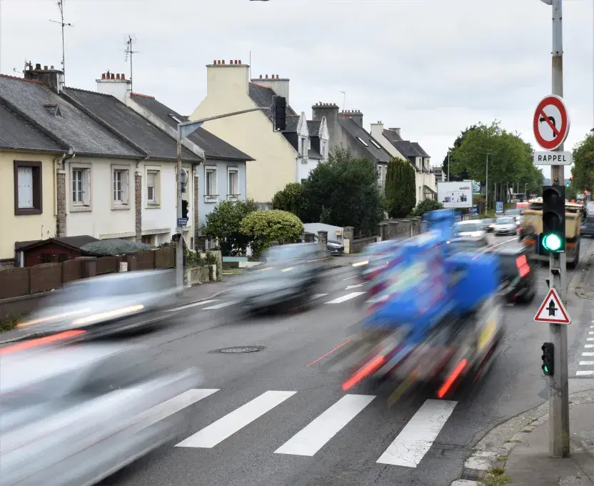 Des voitures passent à grande vitesse à côté d'habitations.