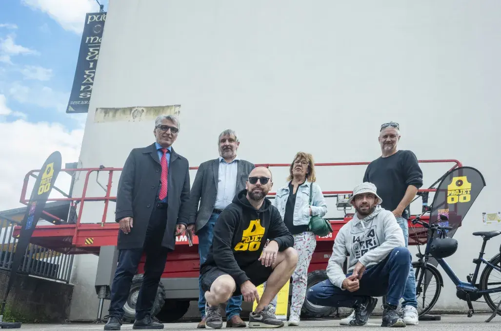 Plusieurs personnes posent devant un mur.