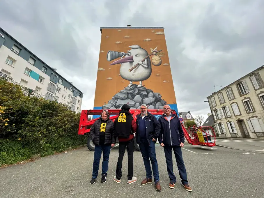 Quatre personnes debout devant une fresque sur un immeuble.