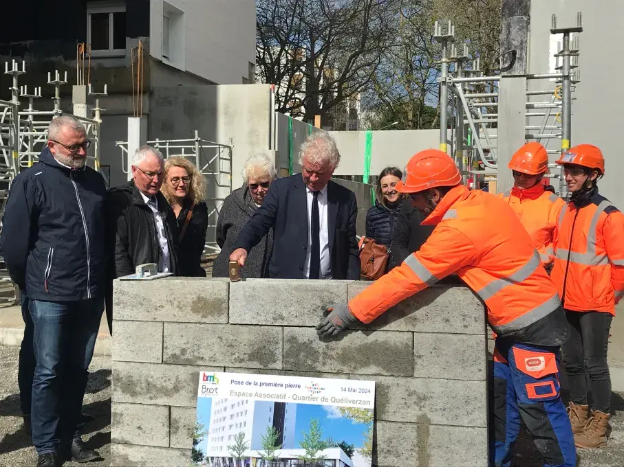 Des hommes posent la première pierre du futur local associatif de Quéliverzan