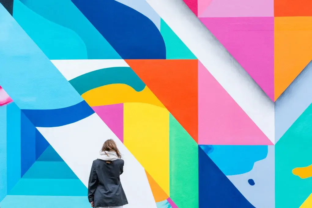 Une jeune femme admire un mur peint. 