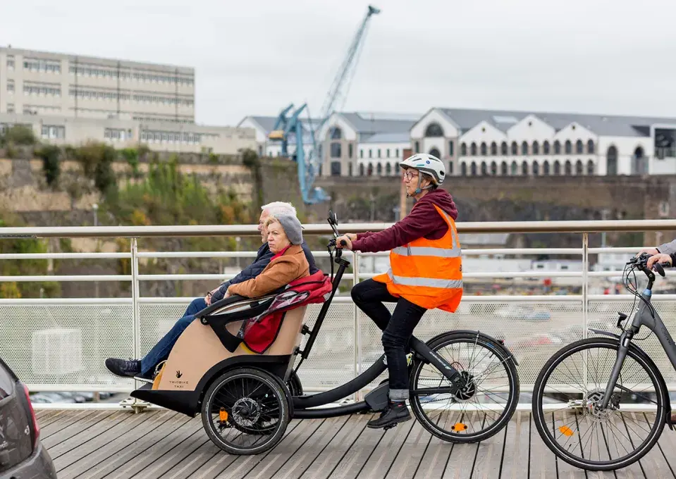 Une femme qui fait du vélo avec un triporteur 