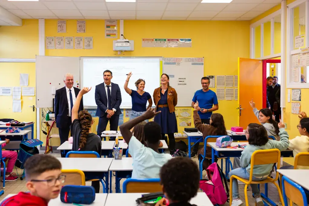 Cinq personnes debout devant le tableau du salle de classe.