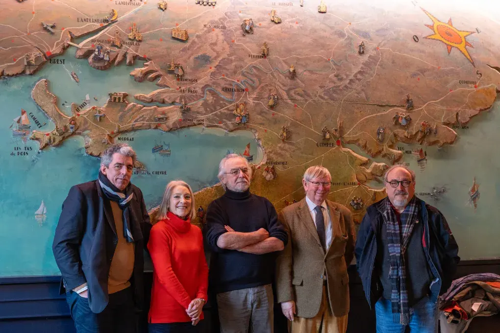 Plusieurs personnes posent devant une grande fresque.
