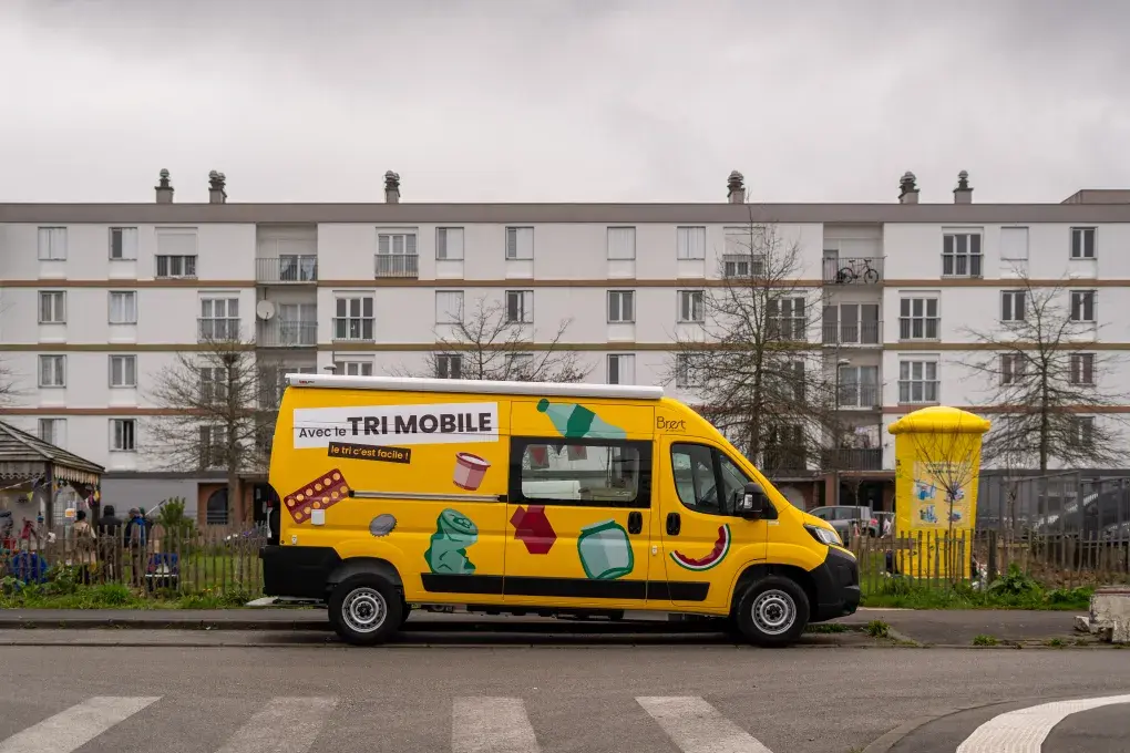 Un camion de tri garé devant des immeubles.