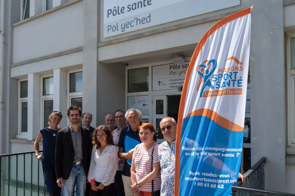 Plusieurs personnes posent devant un bâtiment.