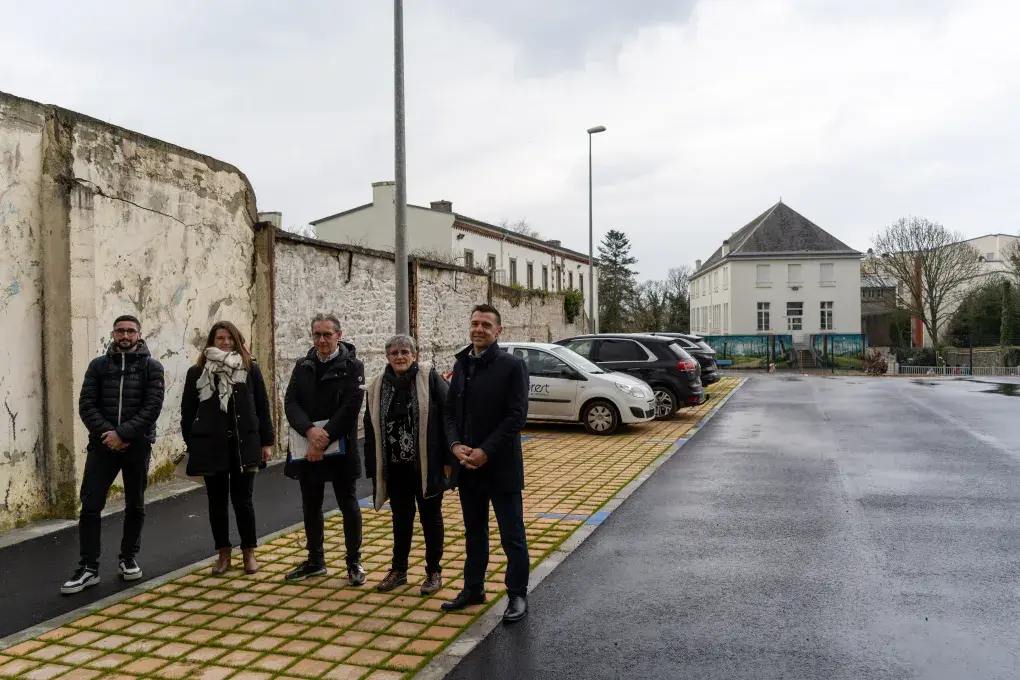 Plusieurs personnes posent sur un parking.
