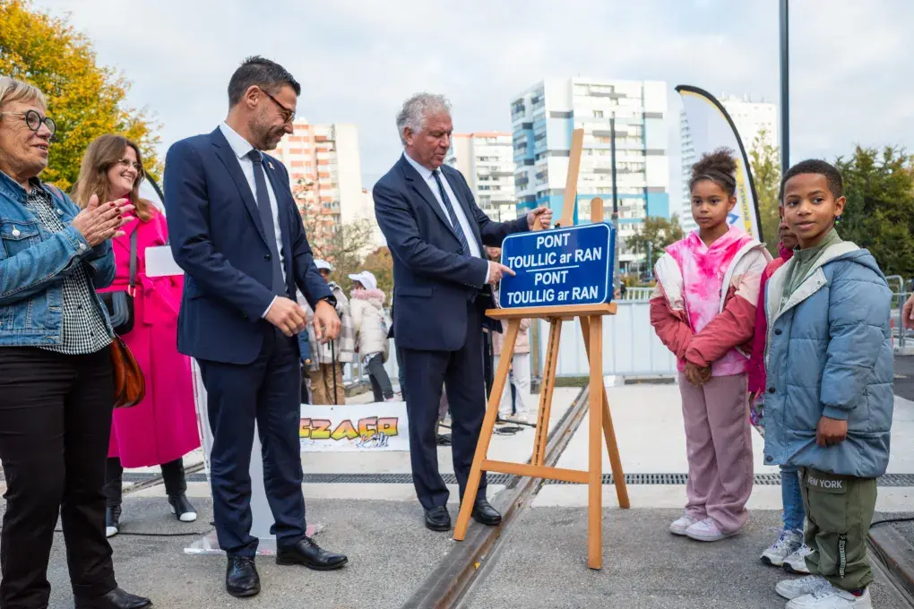Des adultes et des enfants dévoilent une plaque.