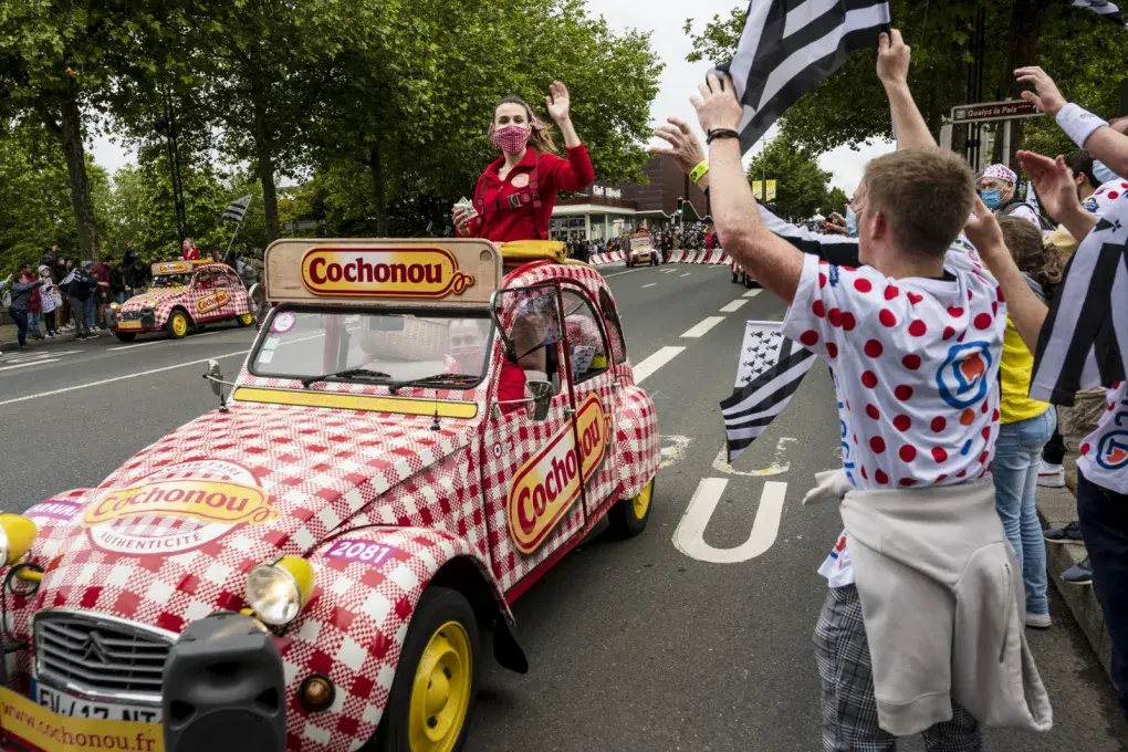 Des spectateurs applaudissent une voiture qui passe.