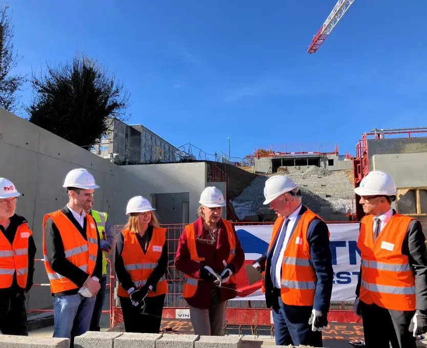 des hommes et des femmes posent la première pierre de la station d'ascenseurs urbains du CHU.