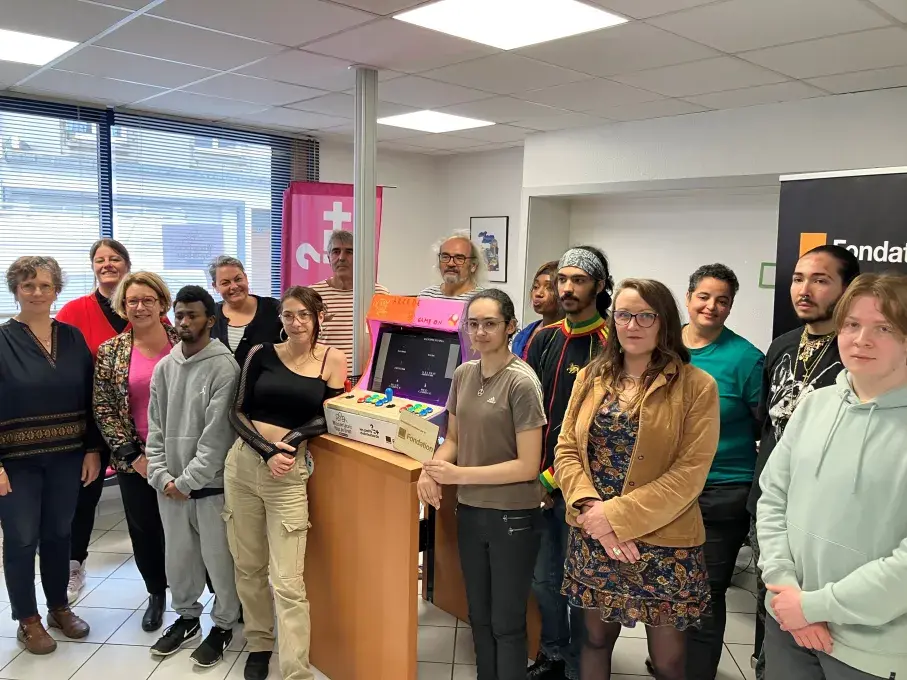 Des femmes et des hommes posent devant une borne d'arcade