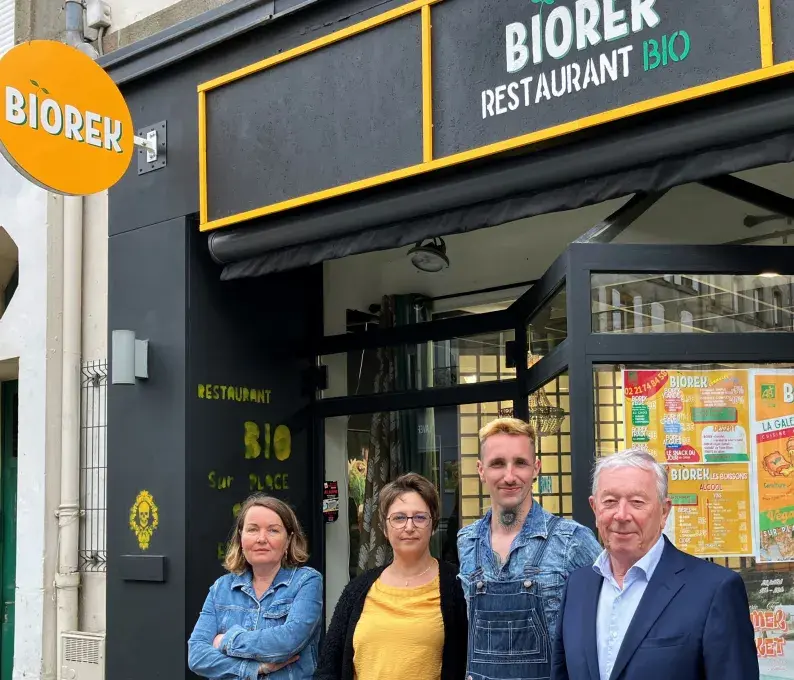 deux hommes et deux femmes posent devant un restaurant