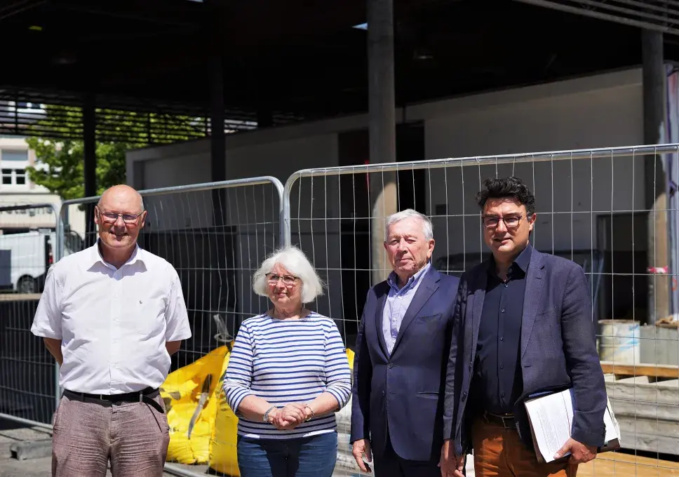Trois et une femme posent devant un chantier