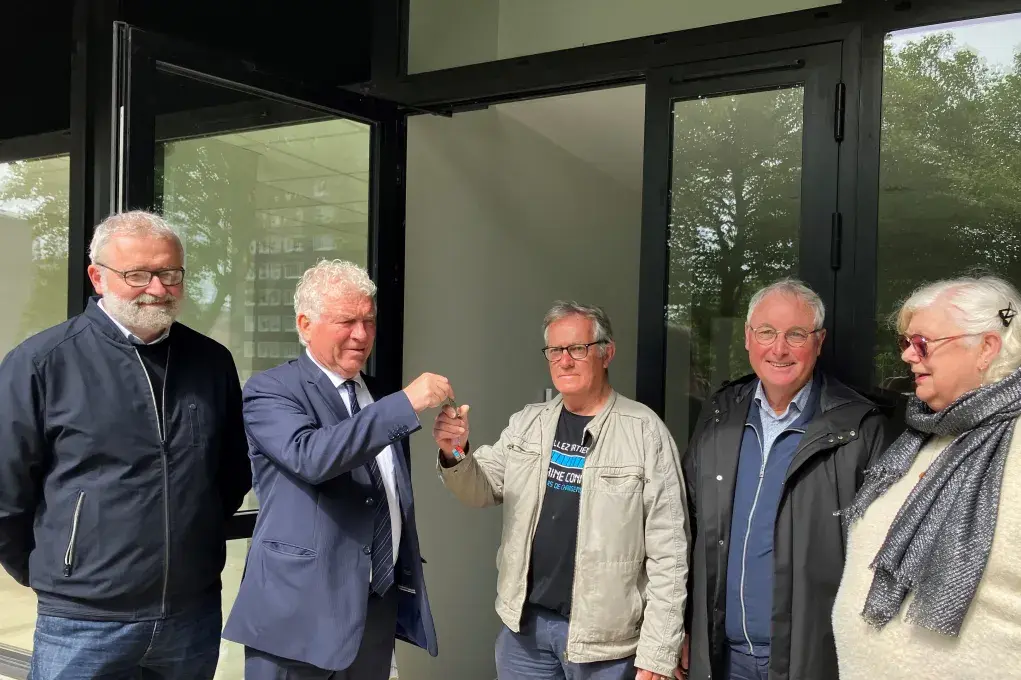 deux hommes échangent des clés devant le local associatif de Quéliverzan