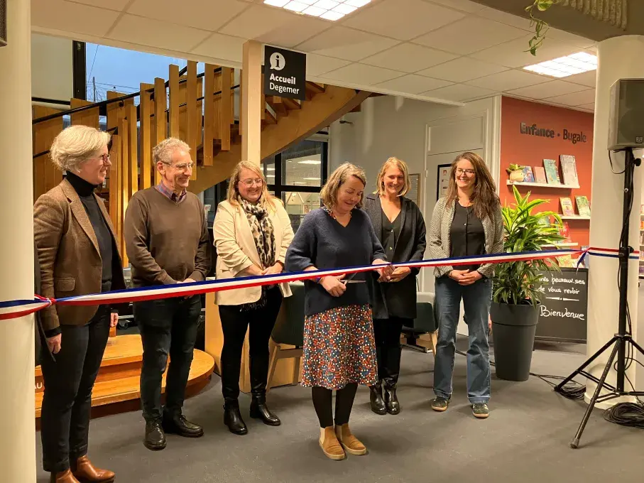 Une femme coupe un ruban d'inauguration dans une médiathèque