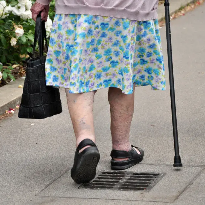 Une femme âgée marche dans la rue.