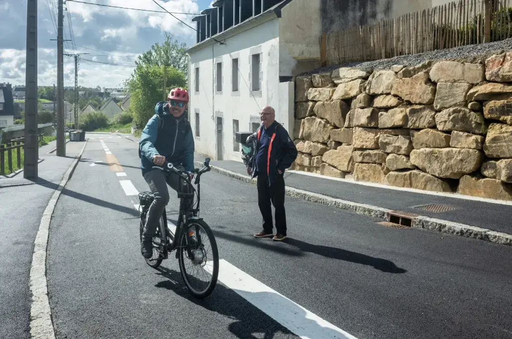 Un cycliste et un piéton se croisent sur une route.