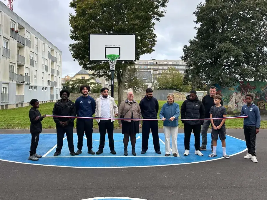 Des personnes coupant un ruban devant un terrain de basket.