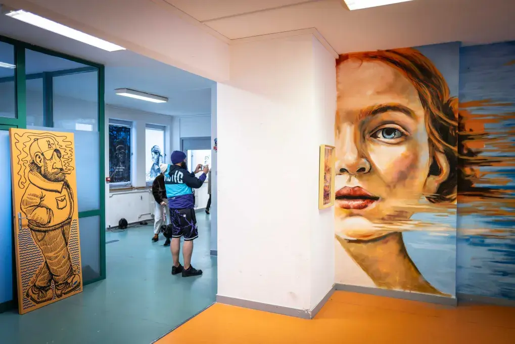 Une salle d'exposition avec, au mur, une œuvre peinte figurant un visage de jeune femme
