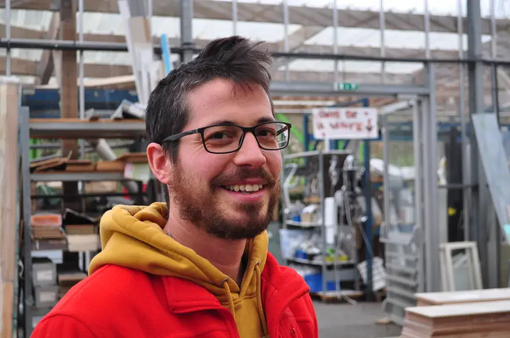 Un homme devant des étagères de matériaux