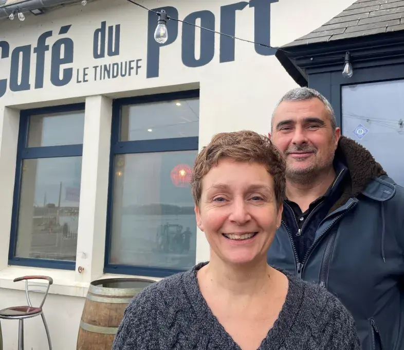 une femme et un homme devant l'entrée d'un café