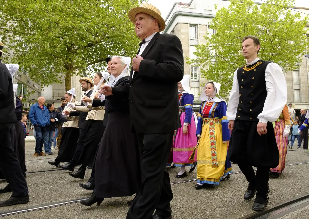 Des personnes défilent en costume traditionnel breton. 