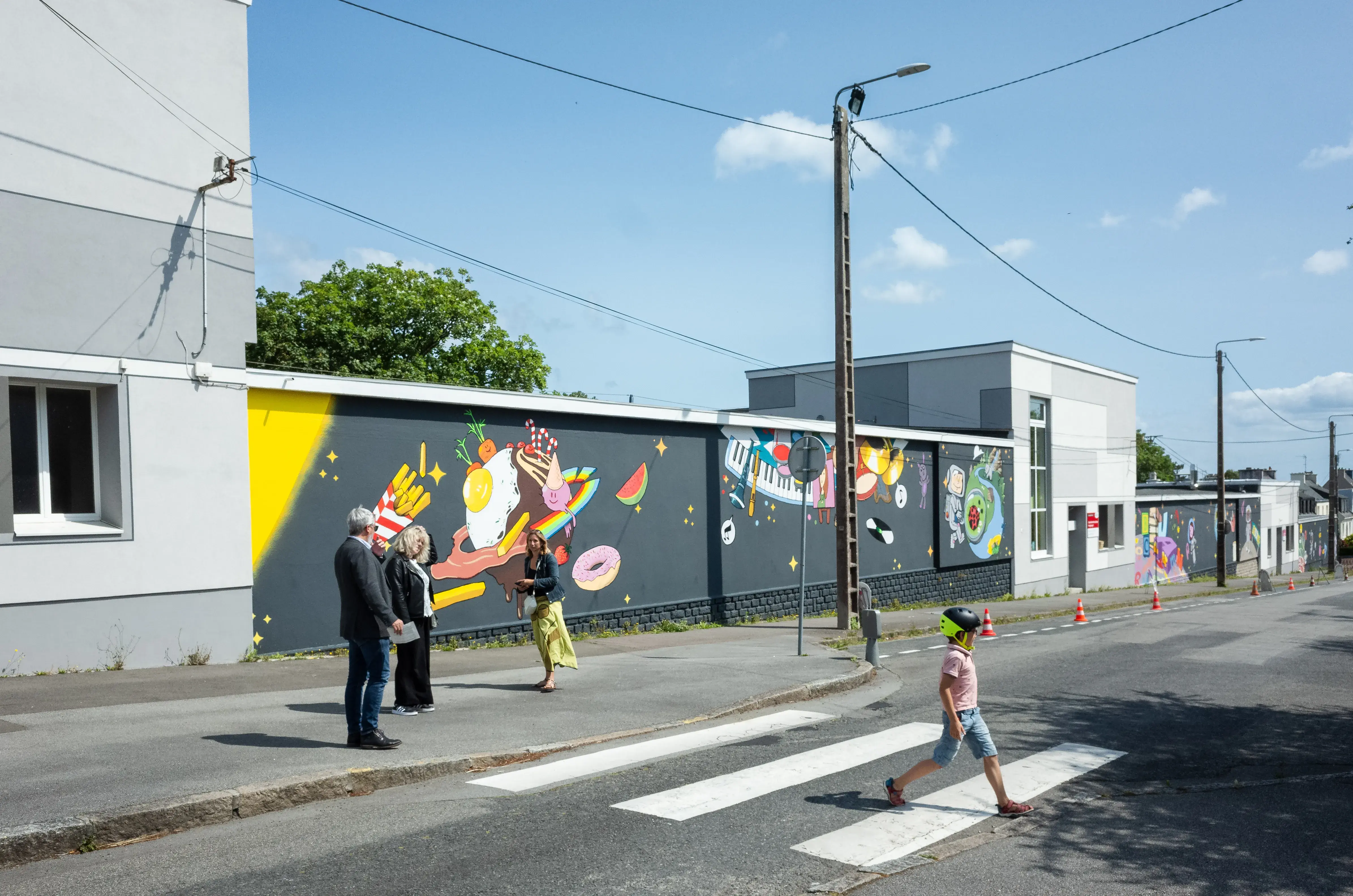 Des personnes marchent devant une grand mur peint.