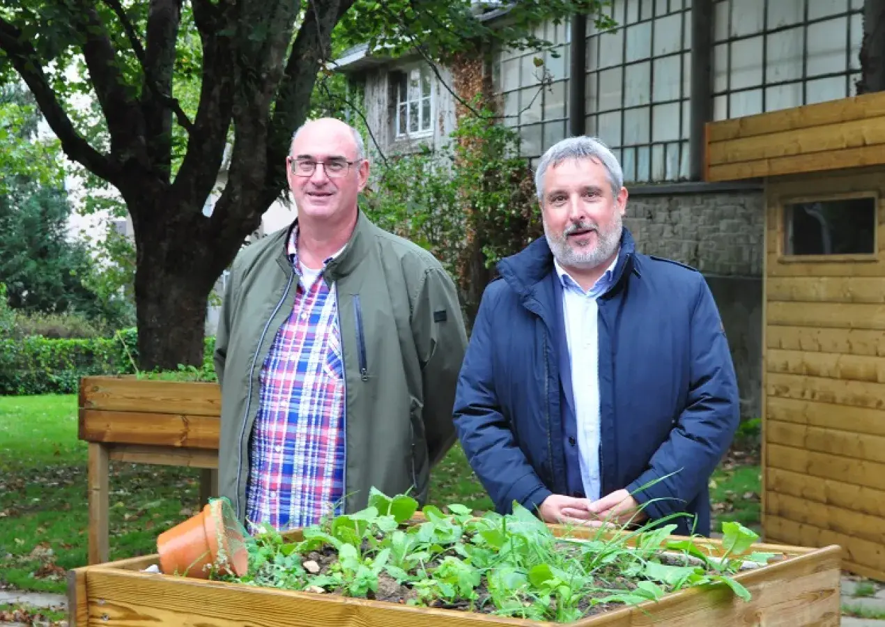 Deux hommes posent devant un bac à fleurs d'un jardin partagé à Brest. 